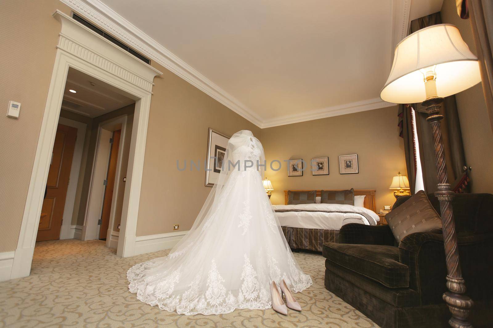 Chic wedding dress and veil on a mannequin in the bride 's gathering room by StudioPeace