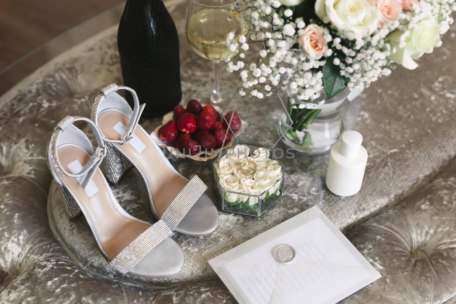 Morning of the bride on the wedding day: shoes, rings, champagne, strawberries and a bouquet.