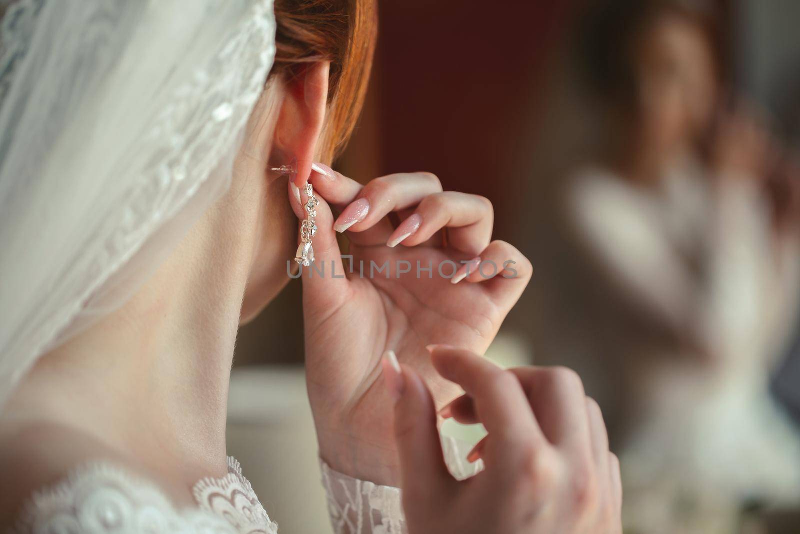 Wedding earrings on a woman's hand, she takes earrings, bride fees, morning bride, white dress, wearing earrings. by StudioPeace