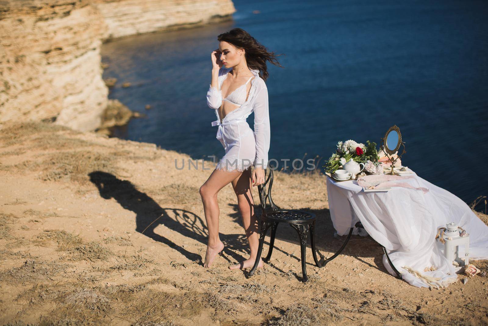 Girl in lingerie on top of a mountain overlooking the ocean. Charges of the bride, bride's morning.