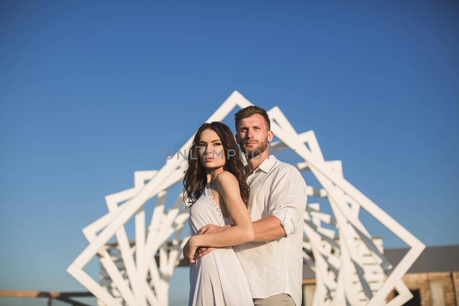 Man and woman posing. Geometric wooden structures. The bride and groom by StudioPeace