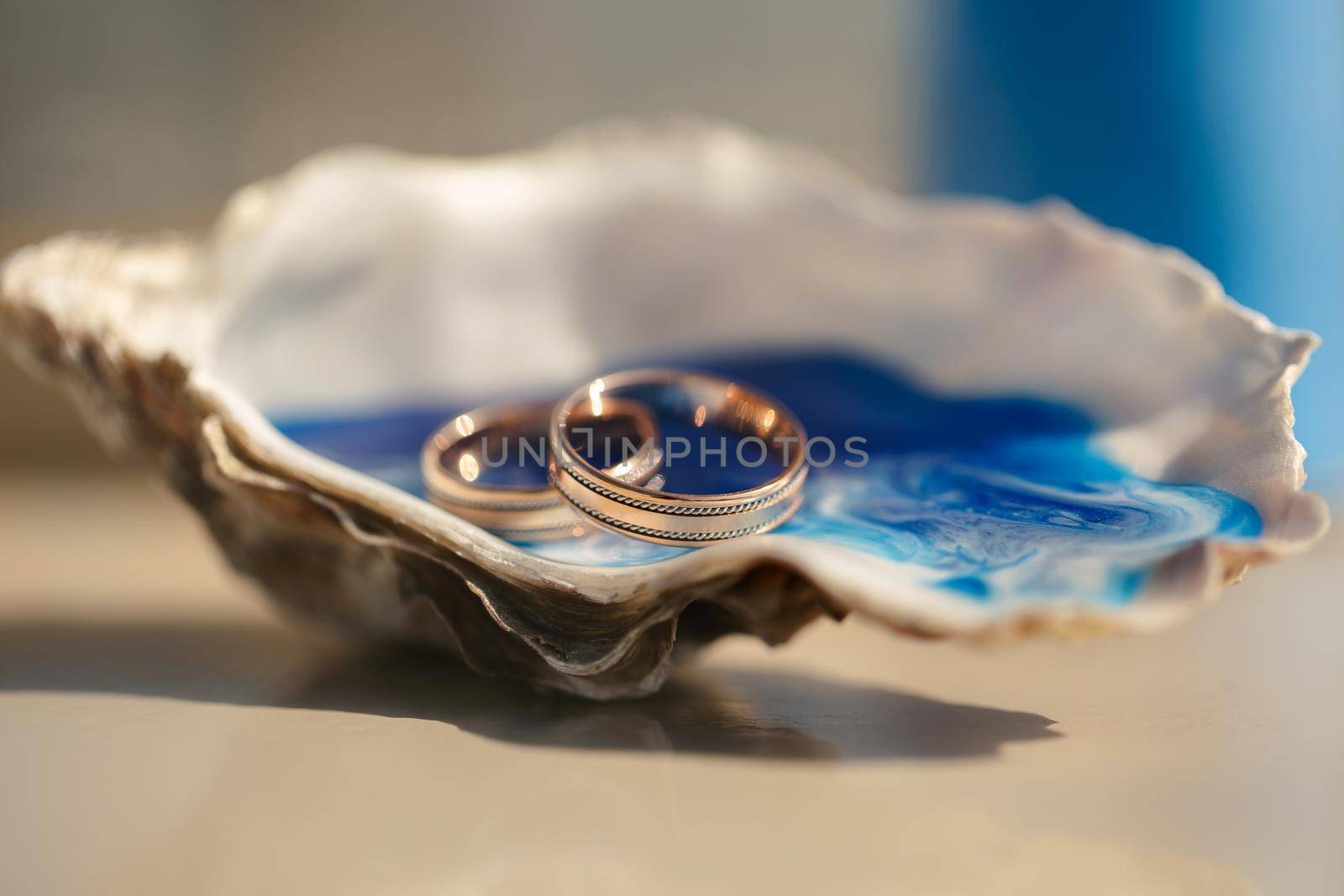 Close-up view of wedding rings in a shell on a table with wedding decor at a wedding ceremony on the beach.