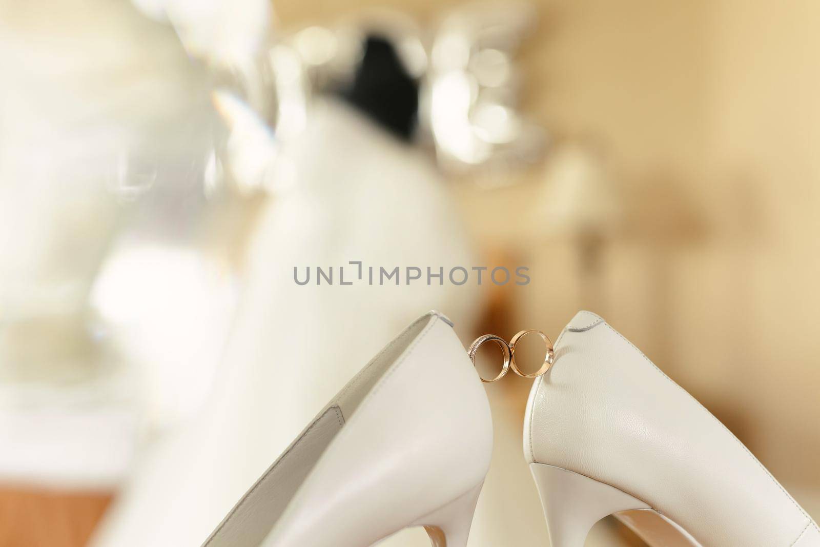 Gold wedding rings between the bride 's wedding shoes. by StudioPeace