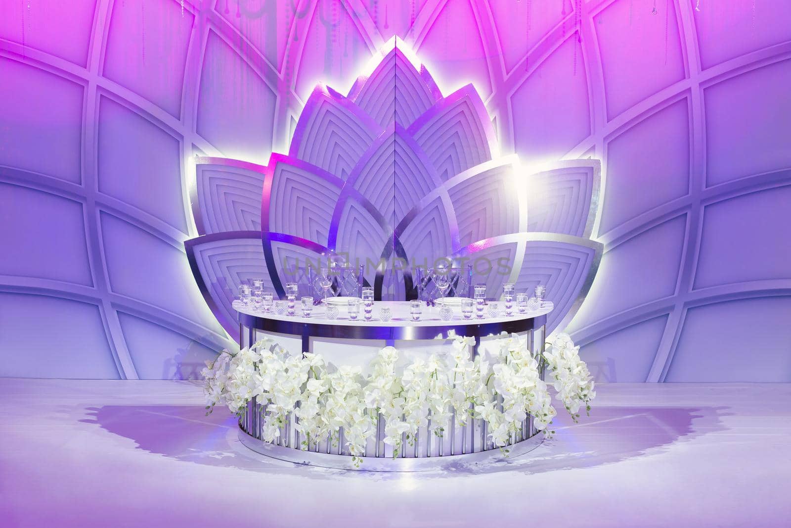 Luxurious wedding presidium in white with silver elements. Groom and bride 's table decorated with beautiful flowers