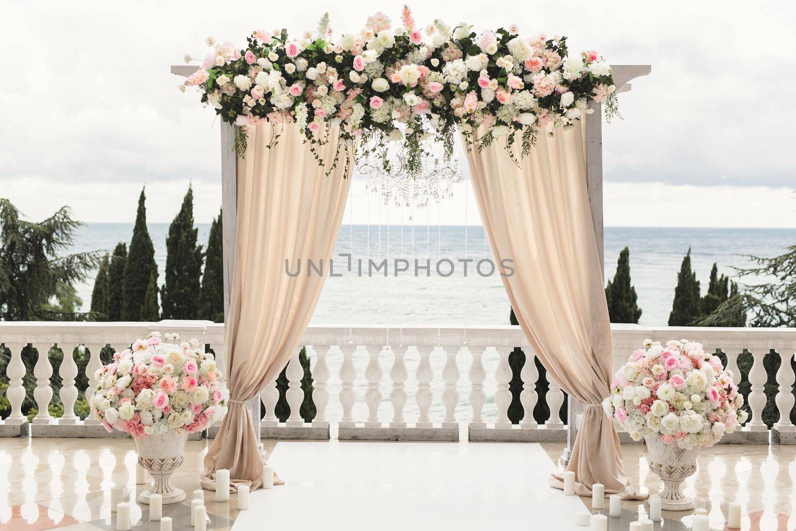 The wedding arch decorated with flowers stands in the luxurious area of the wedding ceremony by StudioPeace