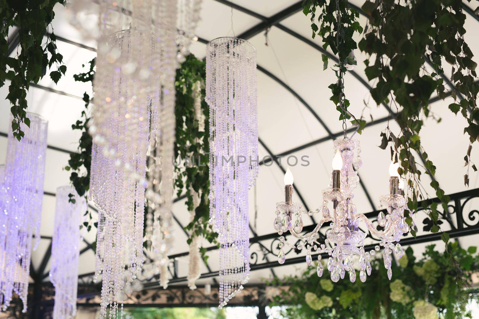 Beautiful luxurious romantic decor for a wedding celebration. The arch is decorated with draped fabric and a crystal chandelier.