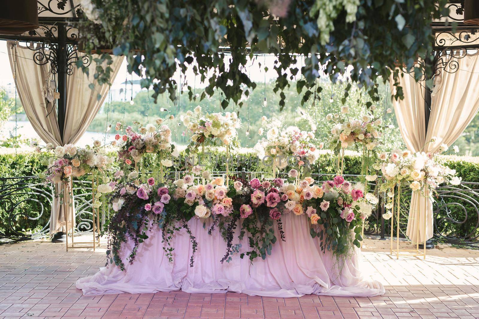 Bride and groom table setting and flower decoration. Presidium of newlyweds outdoors.