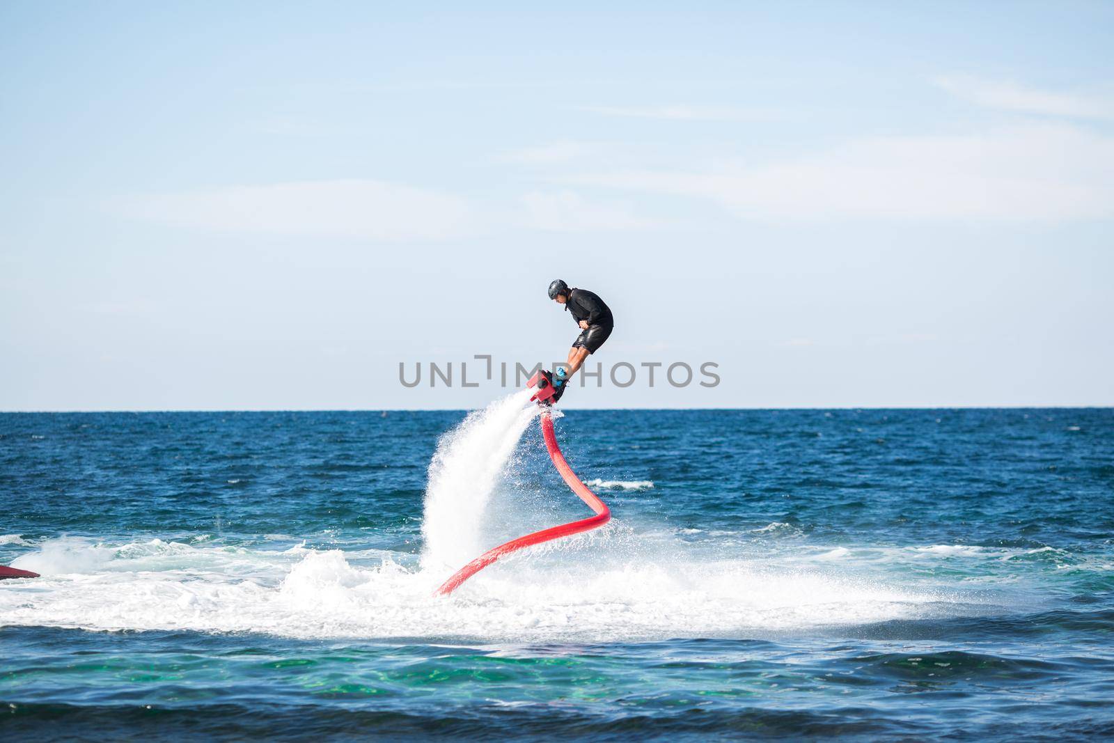 A rider on a flyboard in the ocean does difficult stunts