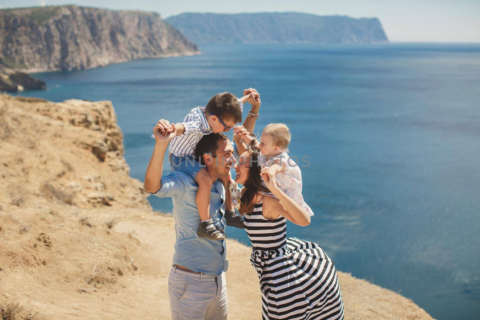 Happy family of four walking in the mountains. Kiss.