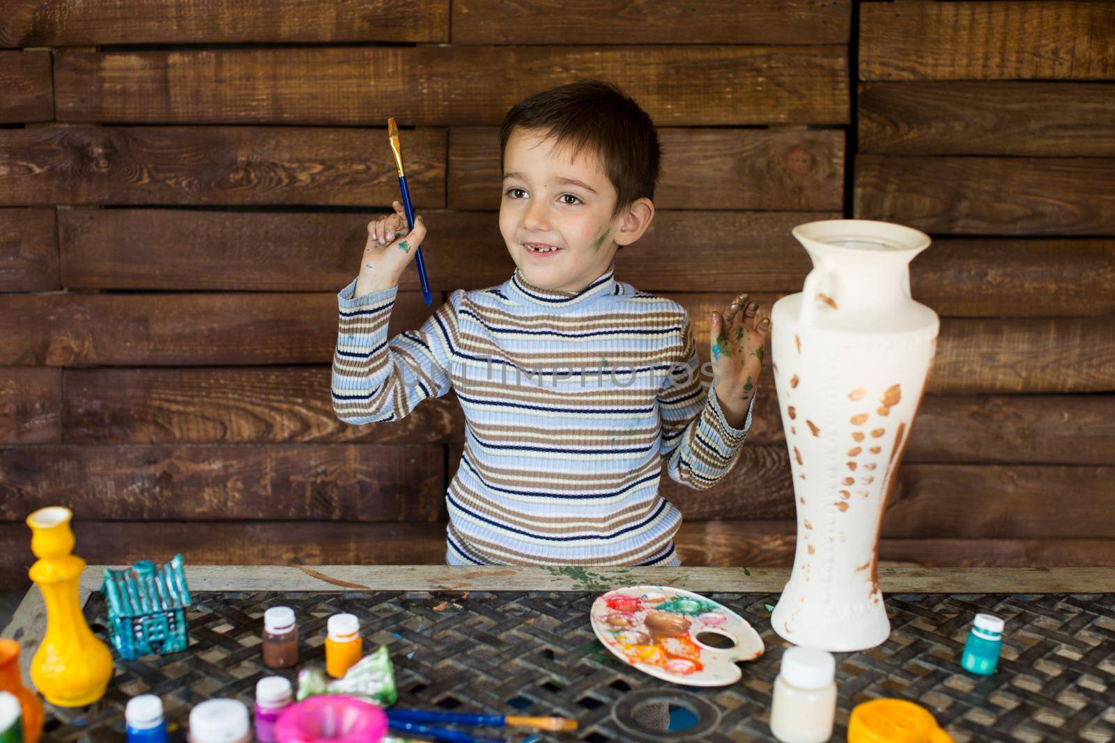 a child paints a vase in the garage. by StudioPeace