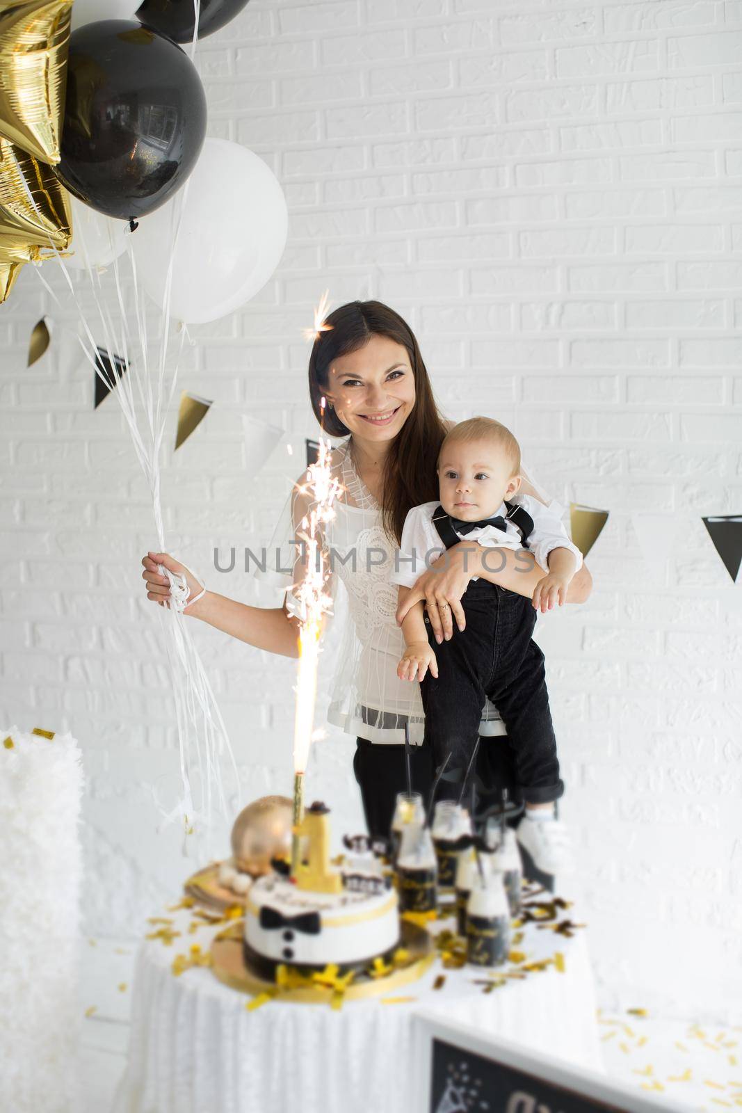 Mother and son celebrating the 1st birthday together laughing and smiling with balloons, a candy bar by StudioPeace