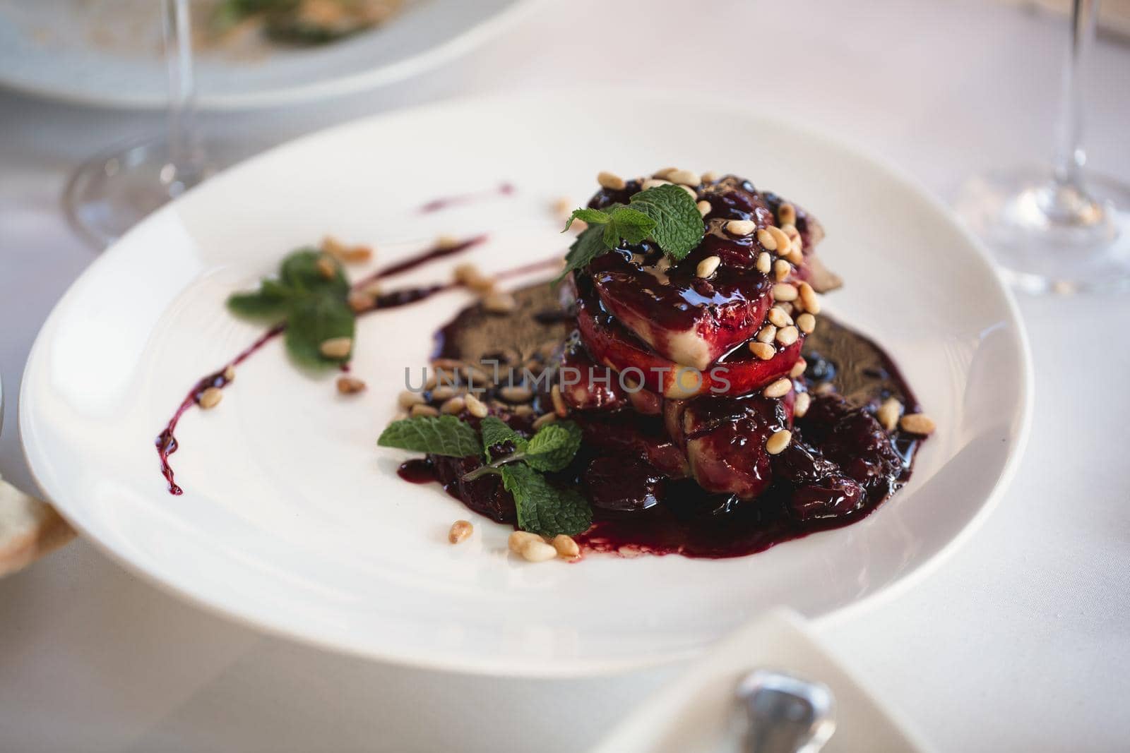 Foie gras with sauce, herbs and nuts on a plate by StudioPeace