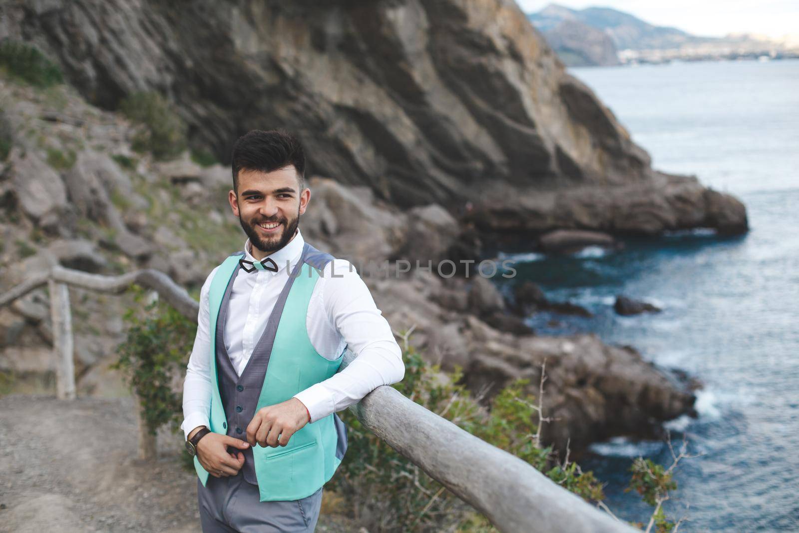 Man in suit in nature. Portrait of the groom. Smiles.