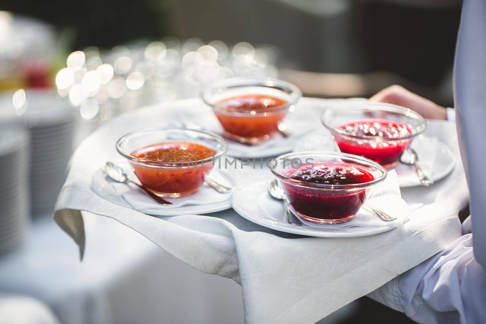 Berry and fruit jam on a tray in the hands of a waiter by StudioPeace