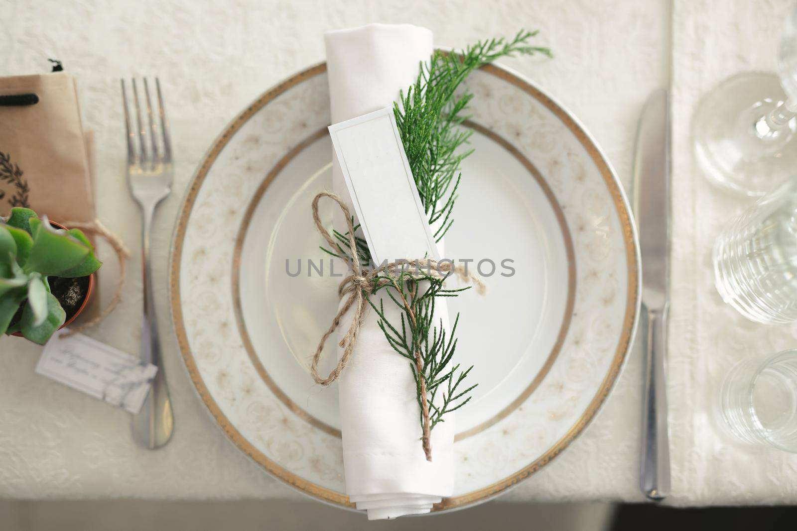 Serving a wedding banquet. A plate with a napkin and a sprig of juniper by StudioPeace