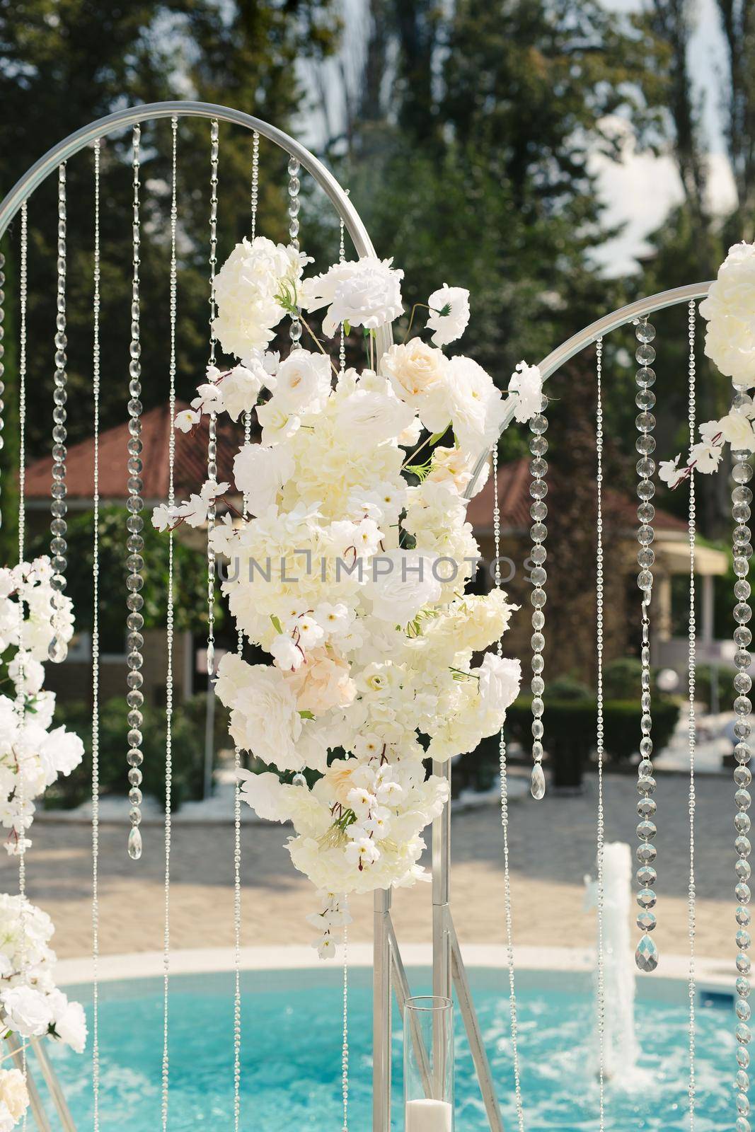 Details of the wedding ceremony made of fresh flowers, sparkling beads. Delicate and beautiful wedding decor for newlyweds.
