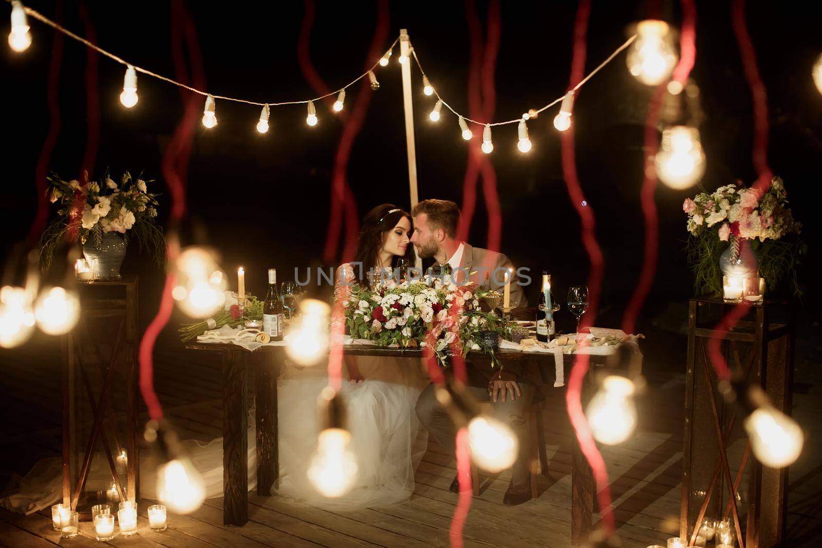 The night wedding ceremony. The bride and groom are sitting at the festive table. Banquet