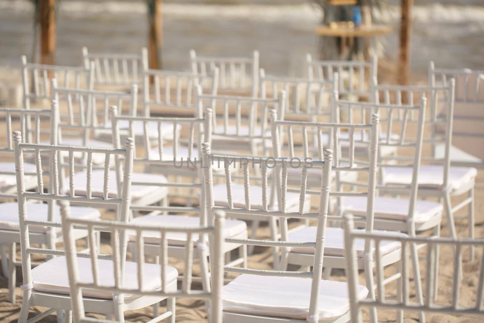 Outdoor area for beach ceremonies with sea view, white chairs, flower arch on a sunny day