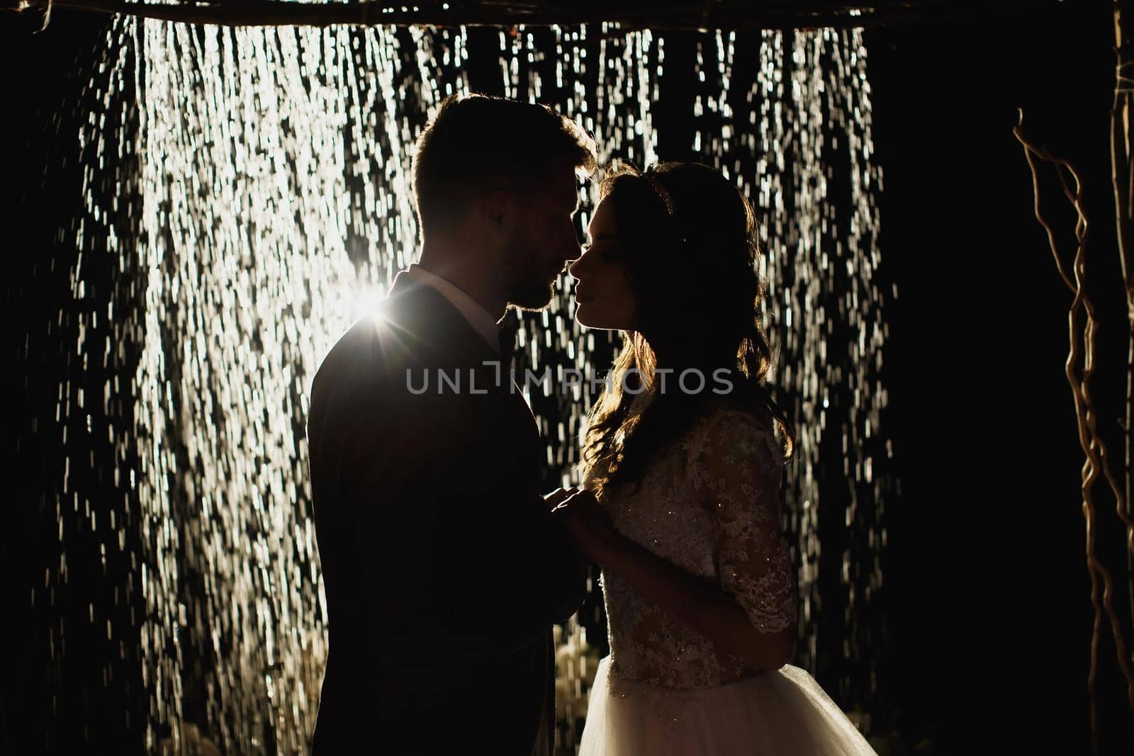 Romantic loving couple newlyweds, wedding against the background of the night sky and rain. the bride and groom stand on the background of the arch with rain.