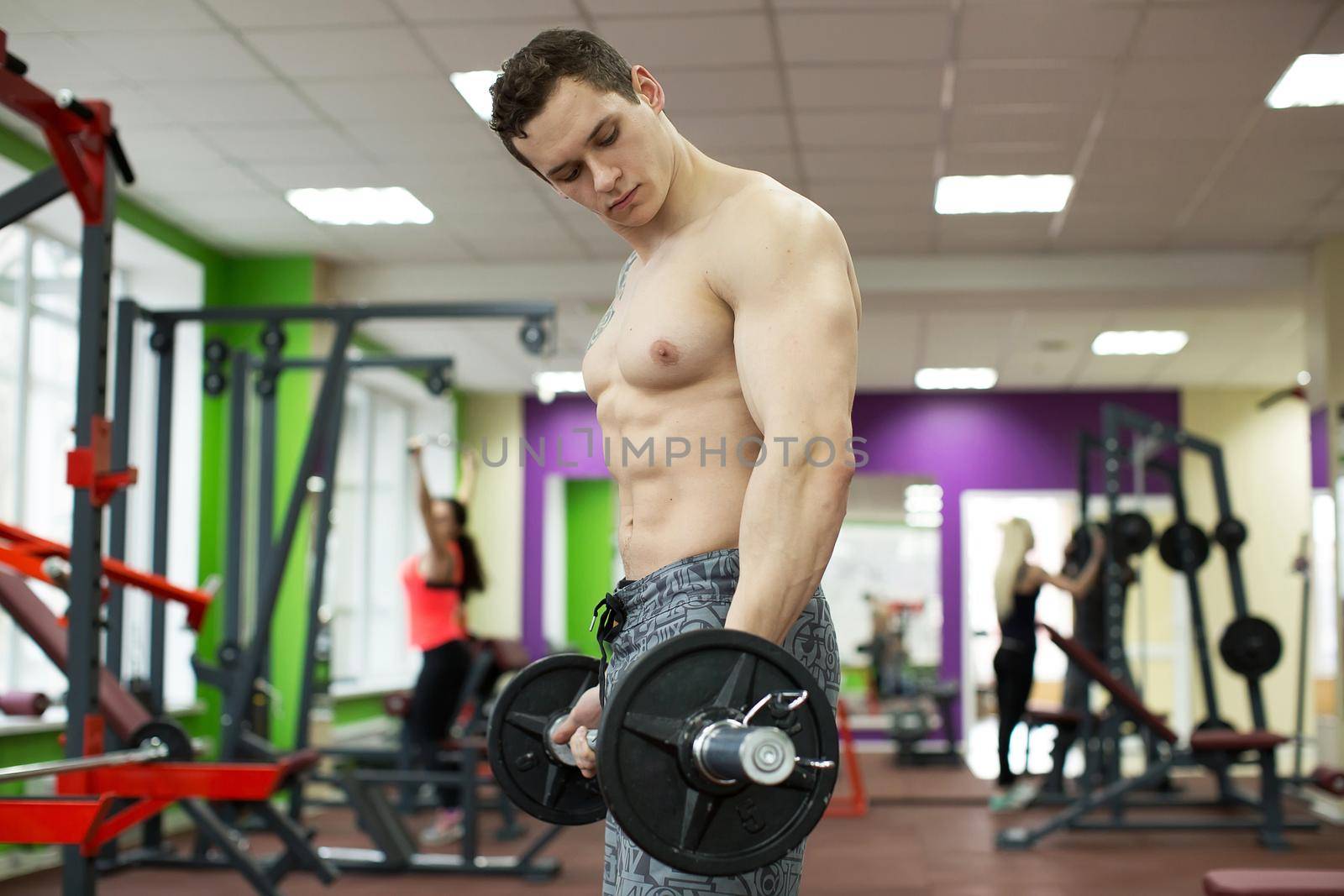 Muscular man working out in gym doing exercises with barbell, strong male naked torso abs. by StudioPeace