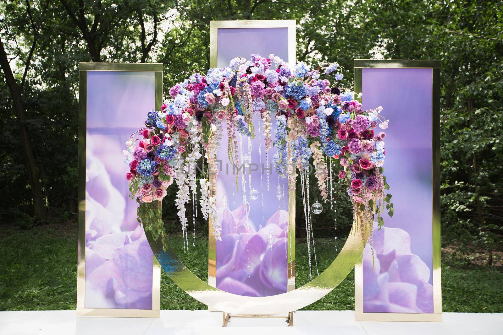 A luxurious round wedding arch with flowers, beads and pendants.