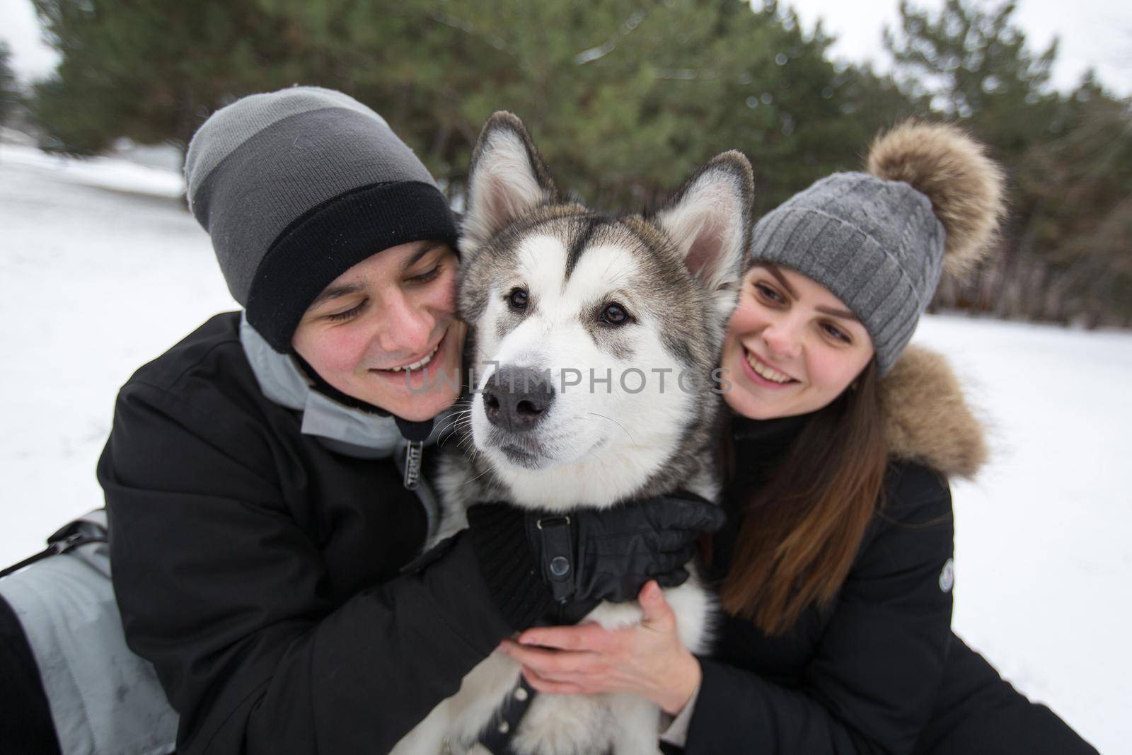 Beautiful family, a man and a girl in winter forest with dog. Play with the dog Siberian husky.