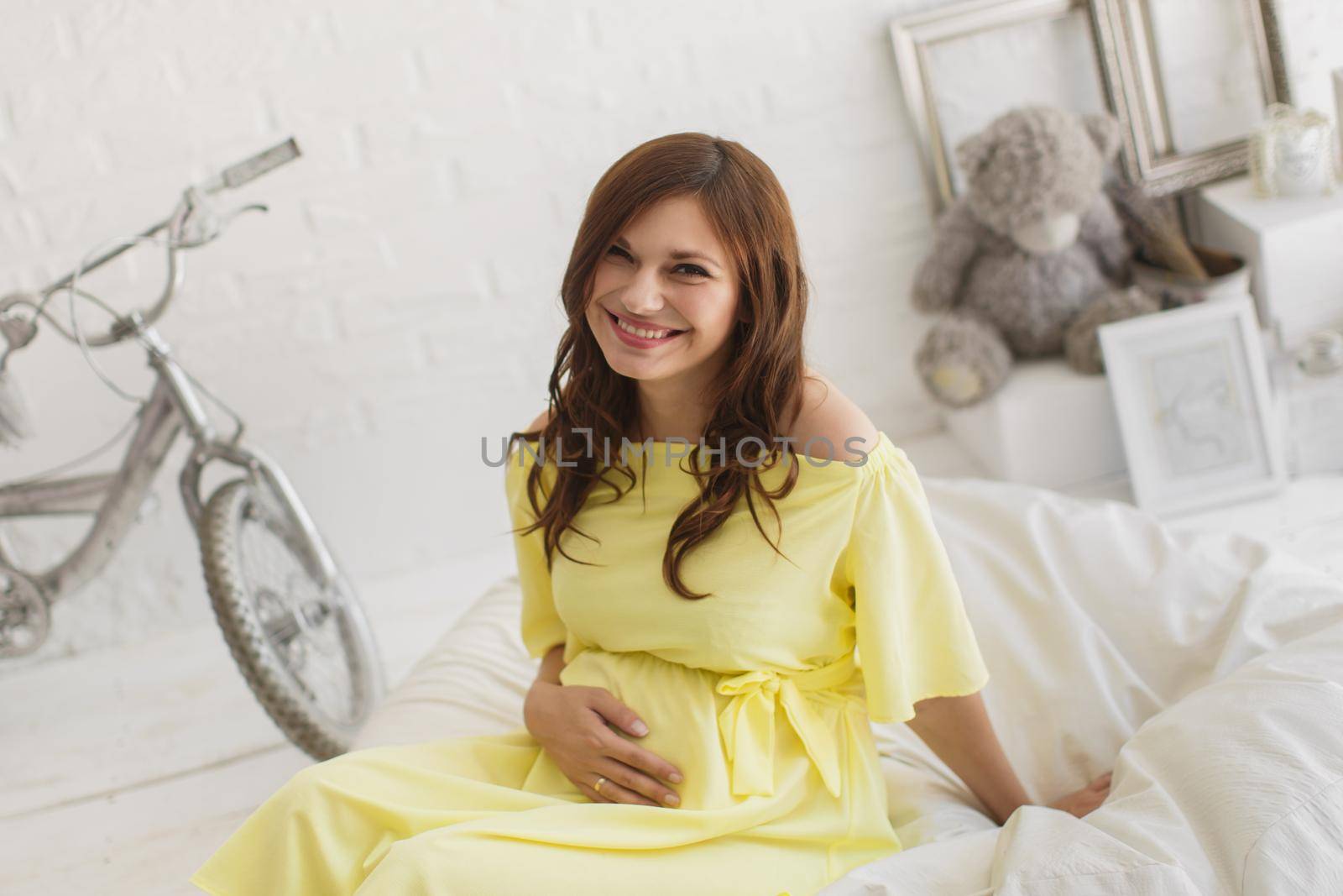 Beautiful pregnant woman in a yellow dress in the Studio by StudioPeace