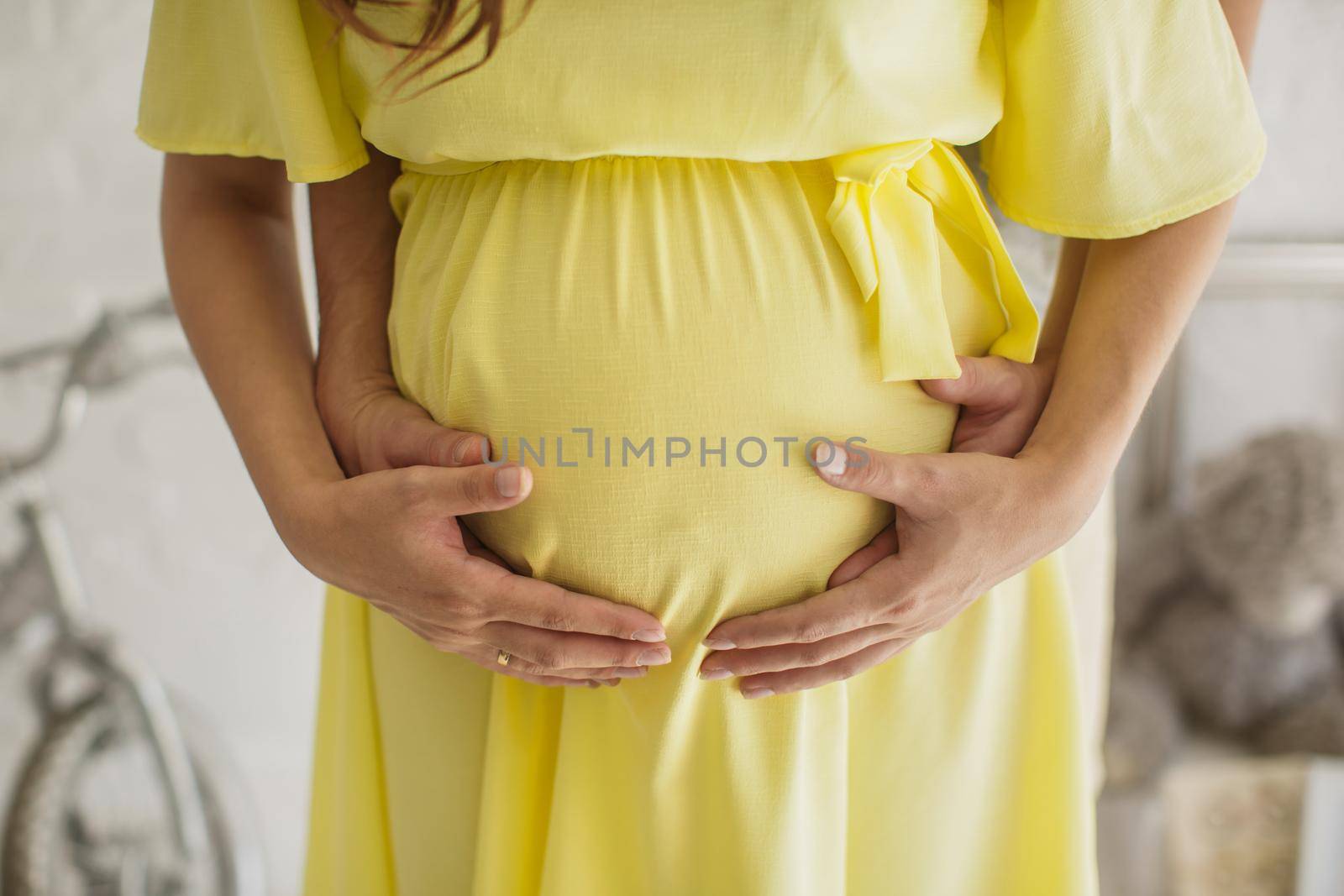 Cropped image of beautiful pregnant woman and her handsome husband hugging the tummy. by StudioPeace