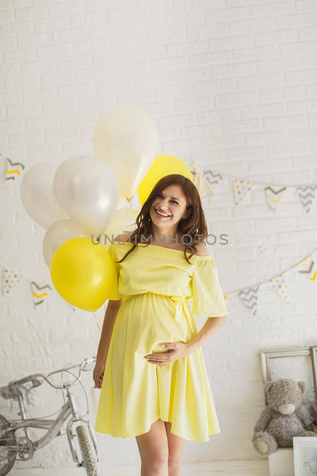 Beautiful pregnant woman in a yellow dress in the Studio.