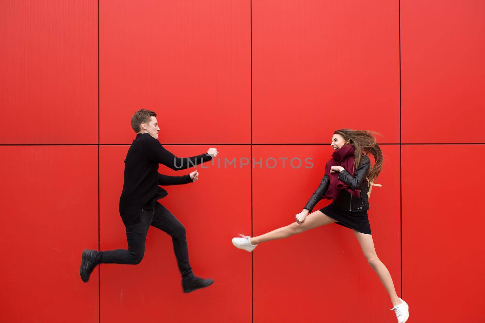 Fight in jump. A man and a woman on a red background.