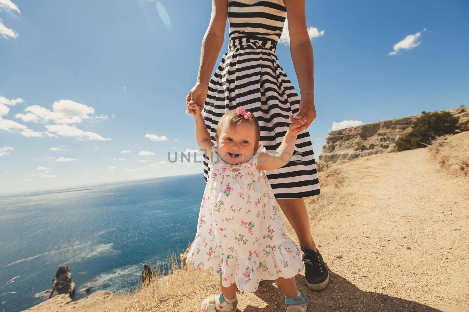 Beautiful mother and daughter walking on top of a mountain. by StudioPeace