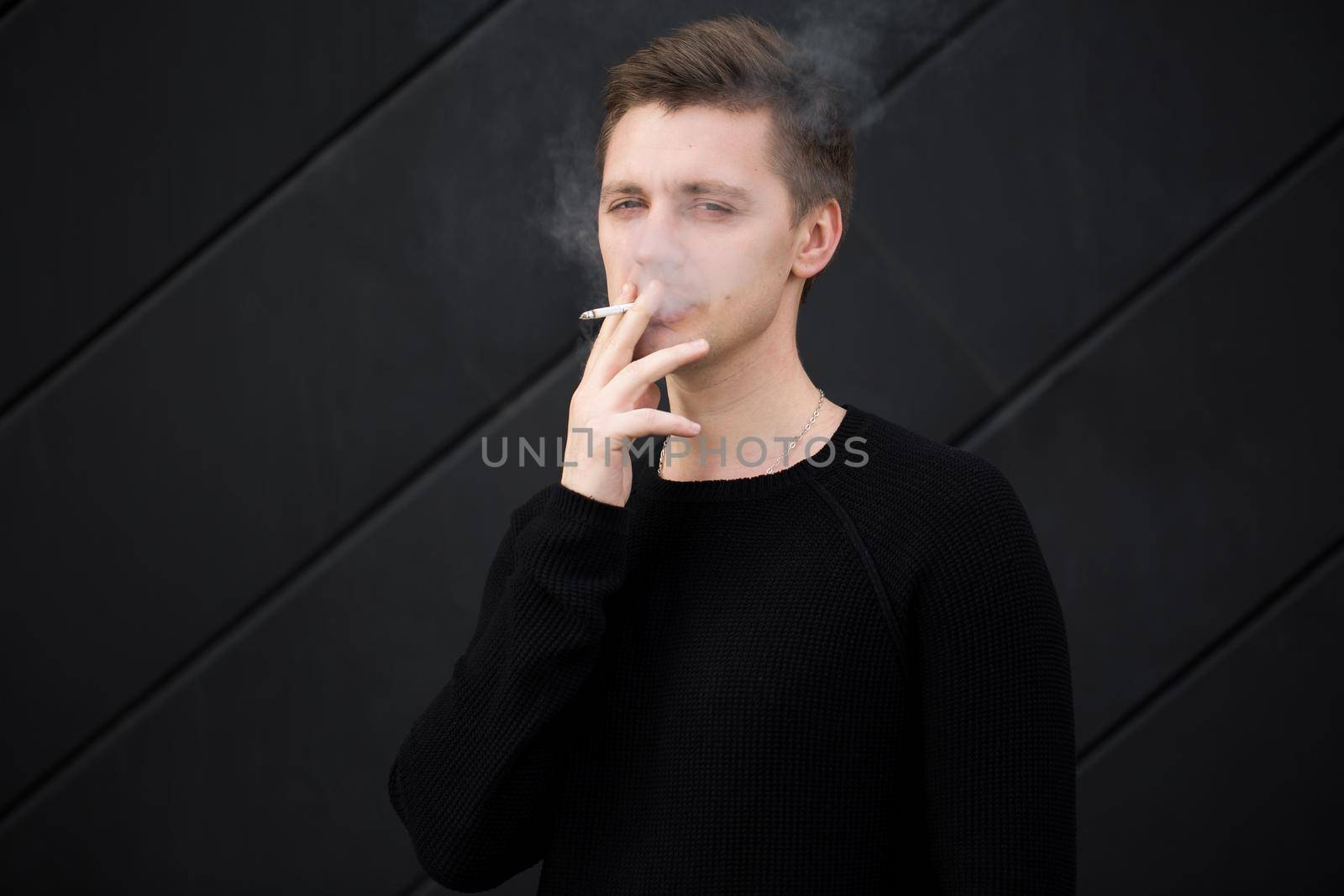 Young handsome guy Smoking a cigarette on black background