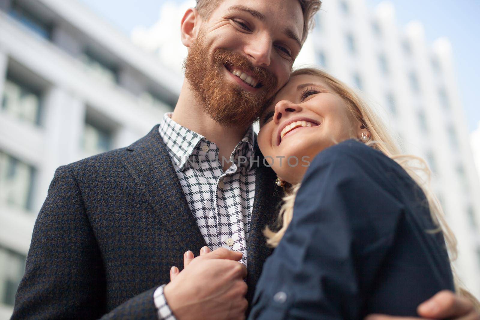 Happy attractive young couple to share a good joke, laughing loudly, embracing each other outdoors in urban environment