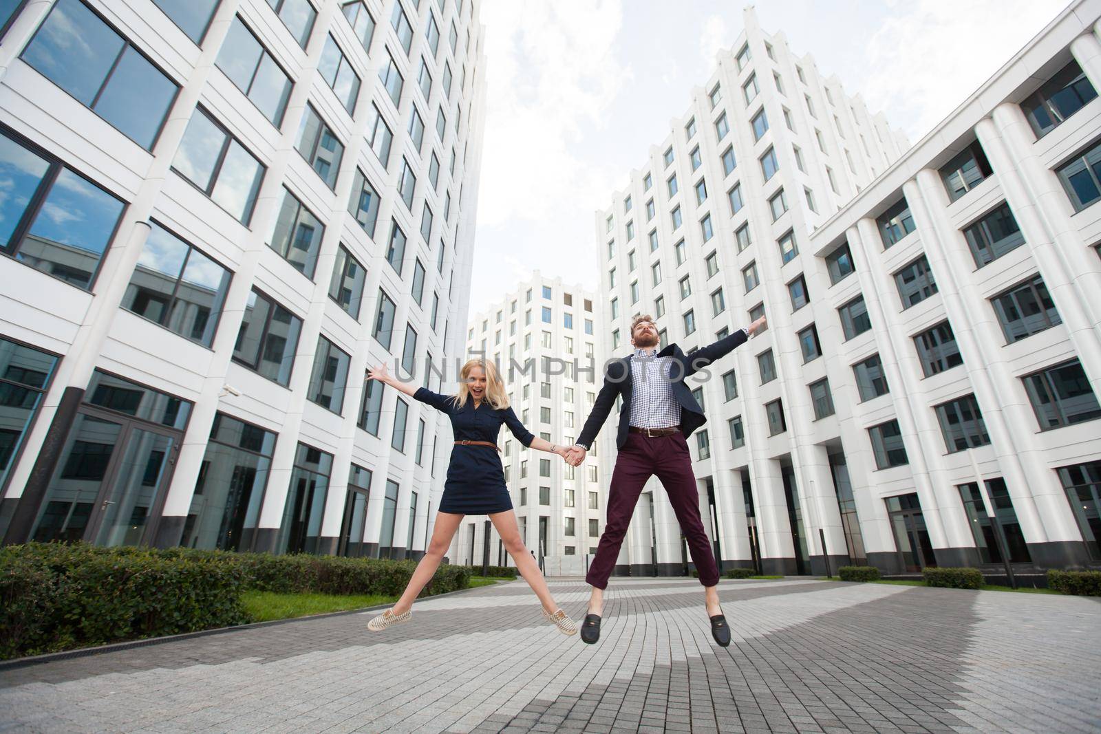 Man and woman are jumping on the background of the building of the business center by StudioPeace