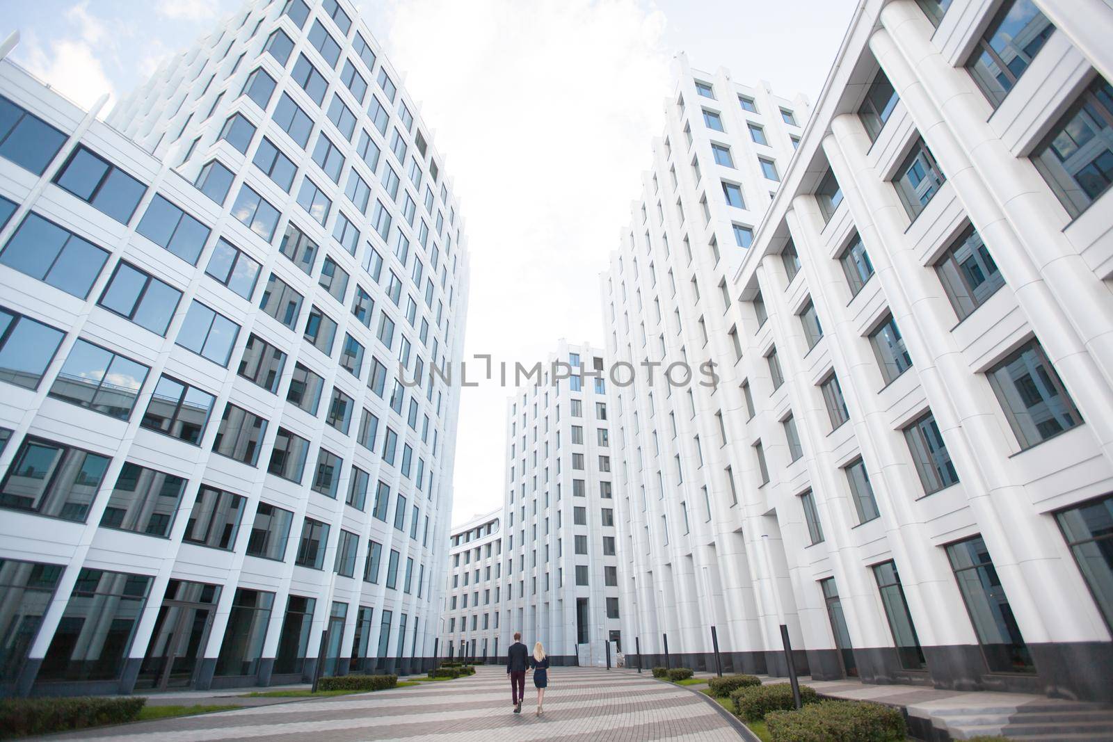 A man and a woman go into the distance, the white background of office building, business center by StudioPeace