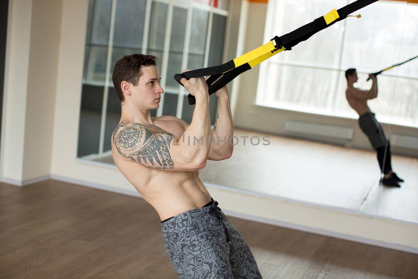 Young man training exercise push ups with trx fitness straps in the gym Concept sport workout healthy lifestyle by StudioPeace