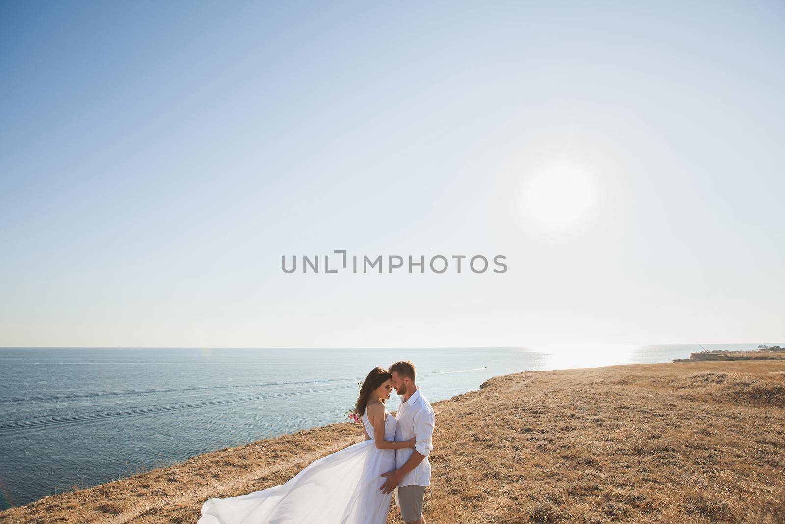 Beautiful young couple standing on the precipice of the mountain. People in white robes by StudioPeace