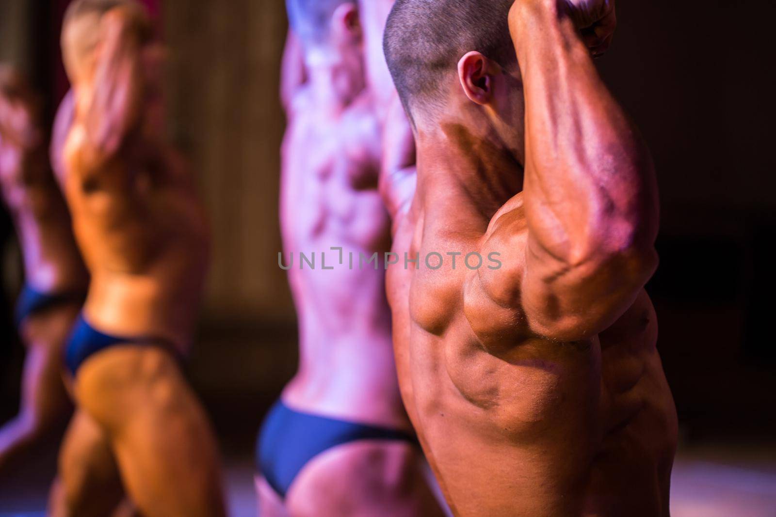 performance athlete bodybuilder to competition. demonstration of biceps your arms from behind closeup. by StudioPeace
