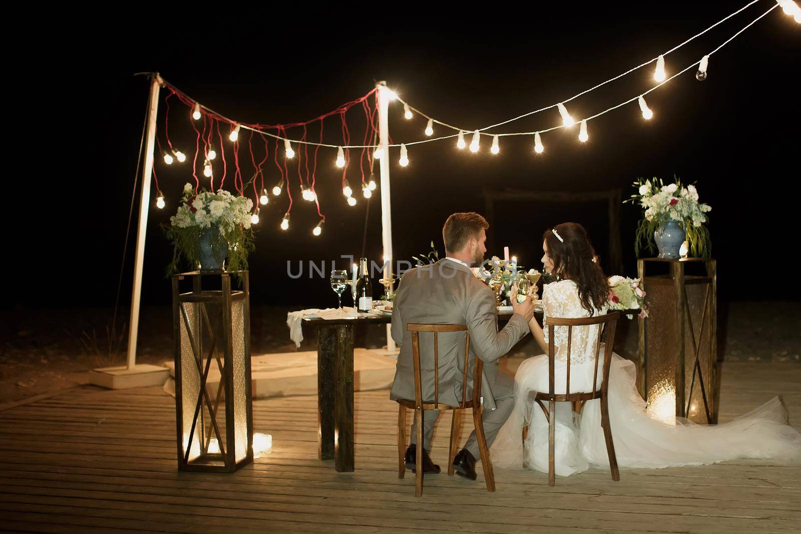 The night wedding ceremony. The bride and groom are sitting at the festive table. Banquet. by StudioPeace
