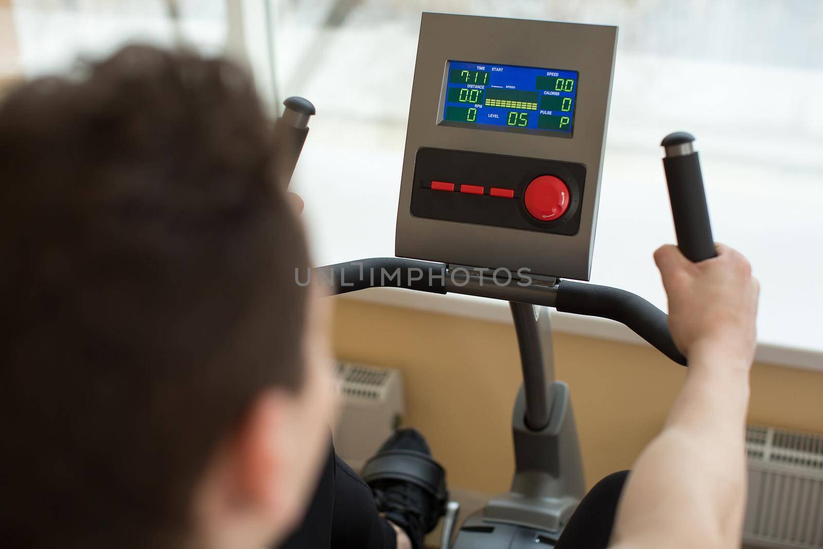 Man on exercise bike in gym. Touch panel. by StudioPeace