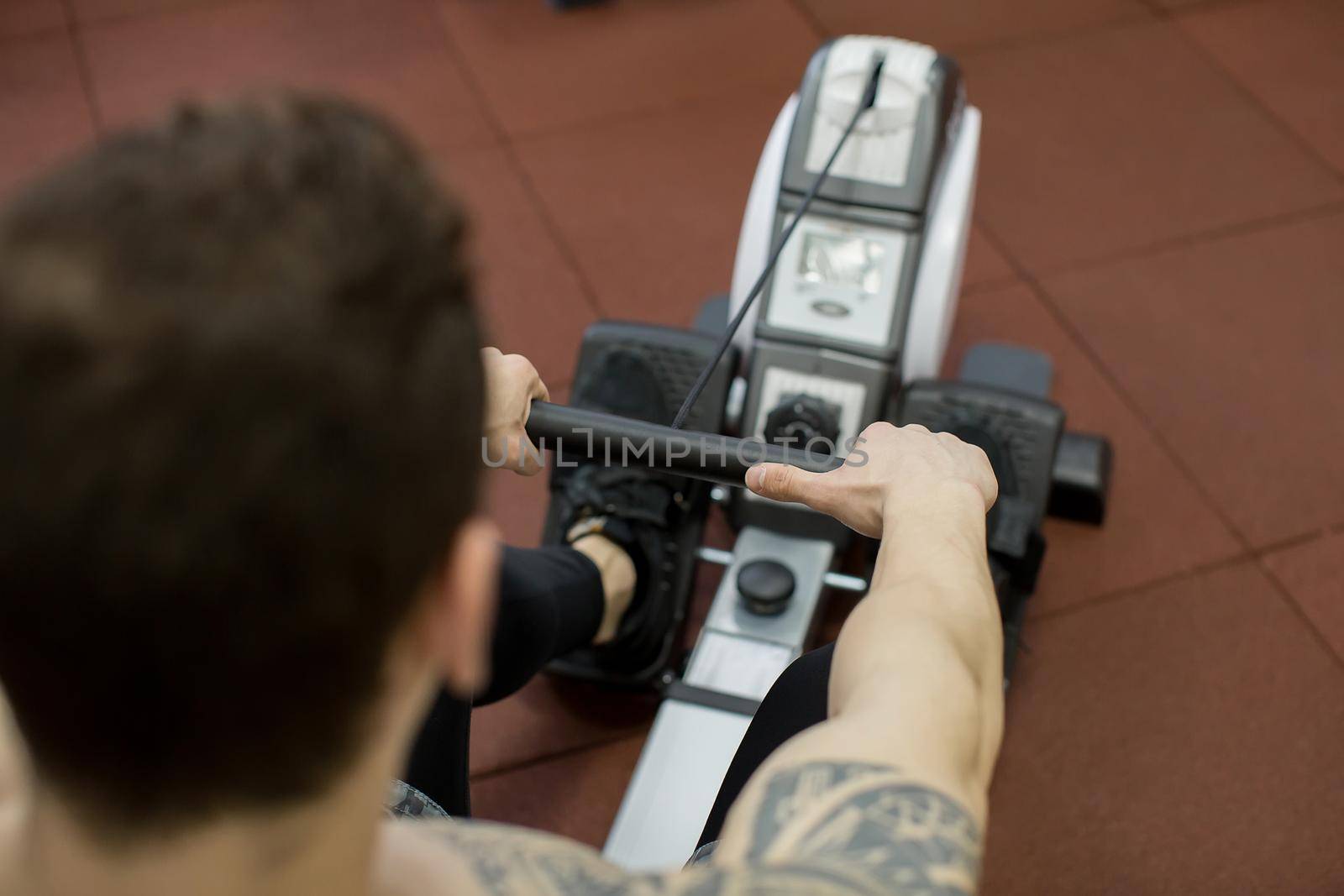 Man running rowing exercise in the gym. by StudioPeace