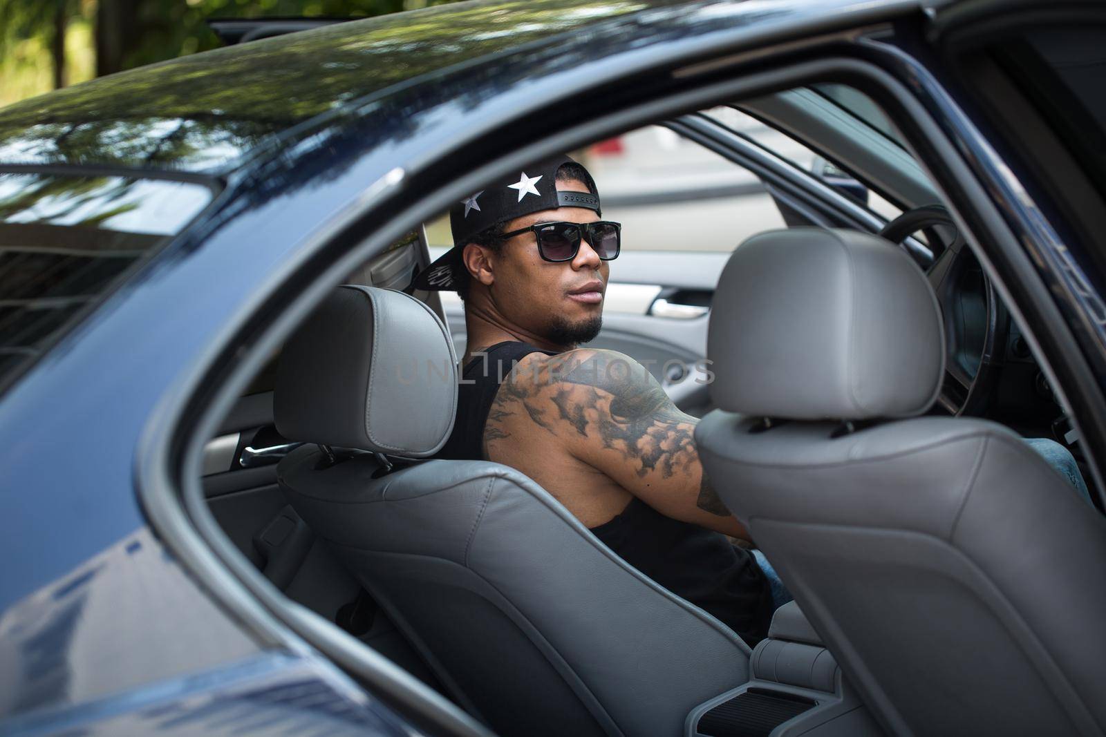 Stylish black man sitting behind the wheel of luxury car.