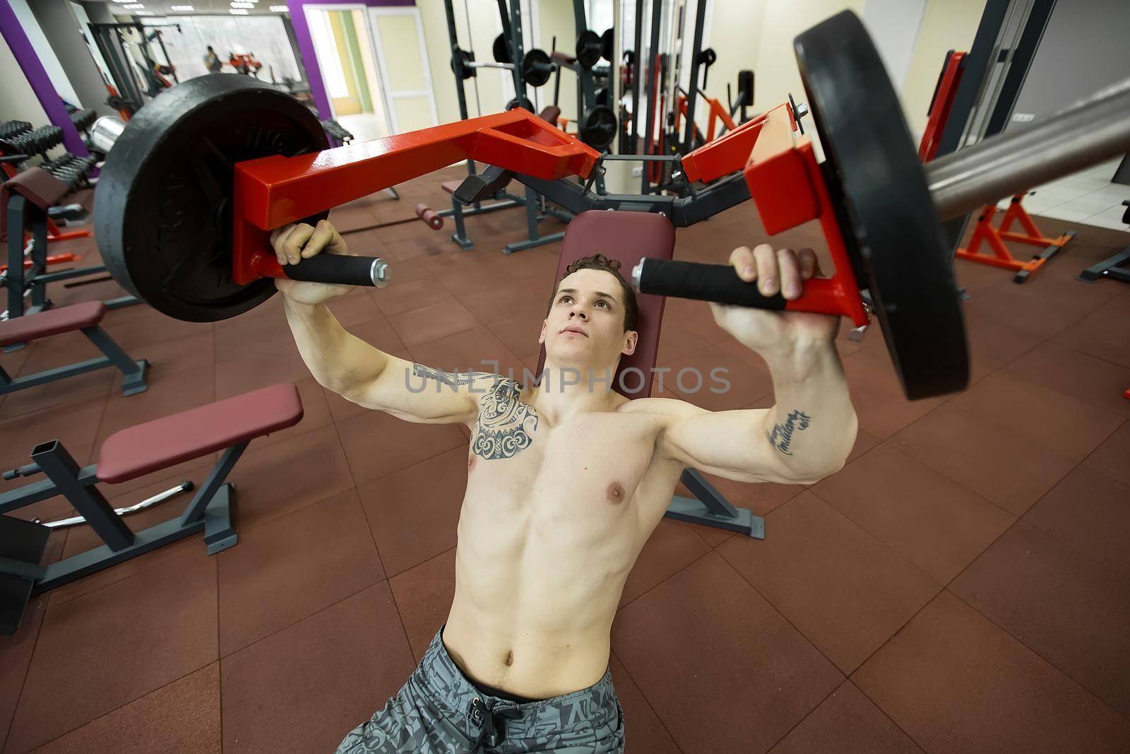 Man doing chest exercises on vertical bench press machine. by StudioPeace