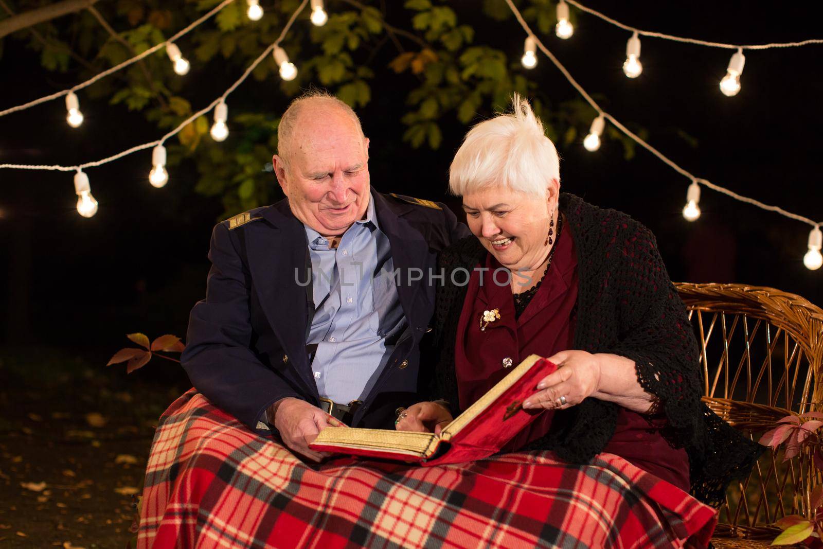 Happy elderly couple in the Park, grandma and grandpa. Look at the photo album by StudioPeace