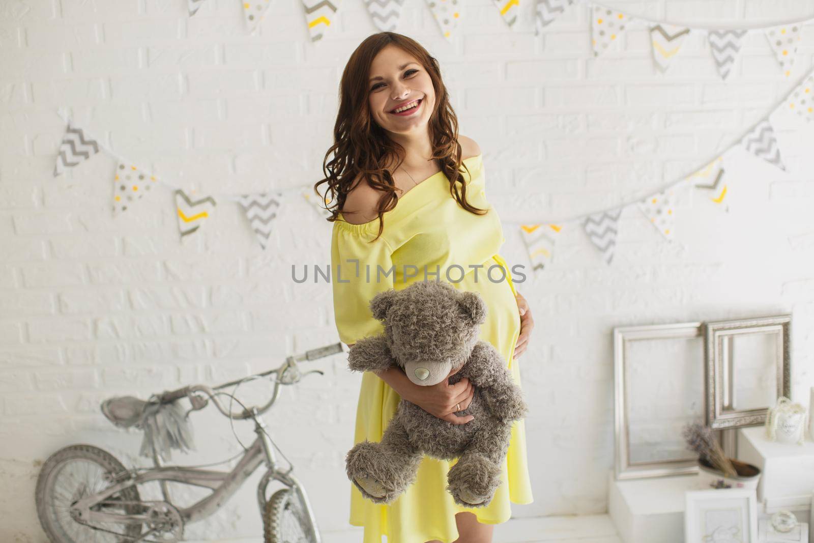 Beautiful pregnant woman in a yellow dress in the Studio.