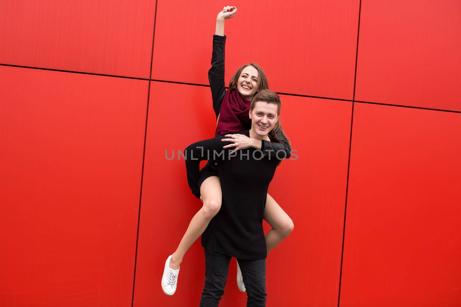 Happy people jump on the background of a red wall. by StudioPeace