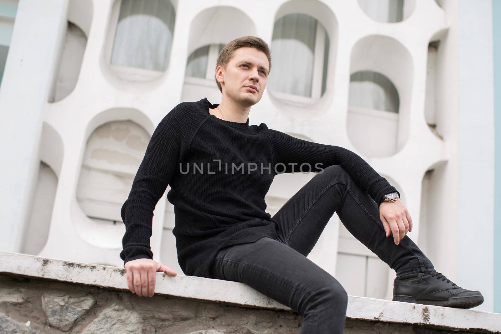 Fashion young man in black clothes on white wall background