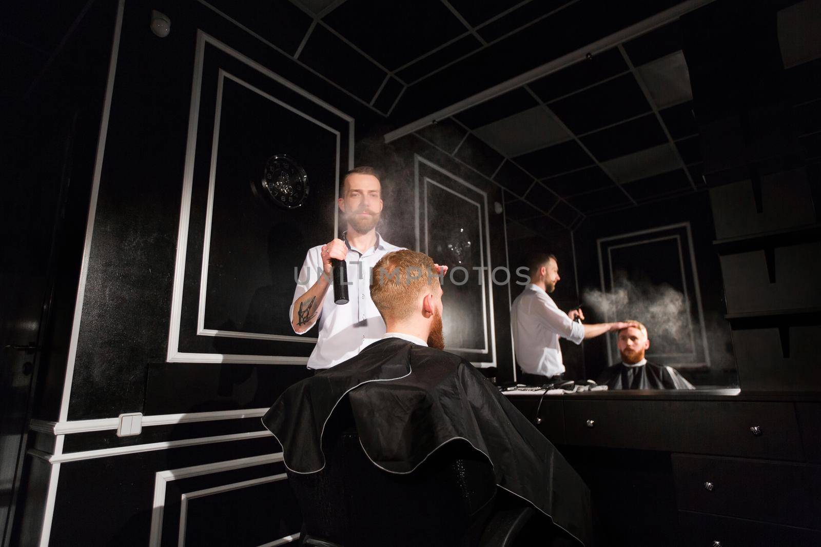 Spraying hair. Portrait of a barber spraying water on the hair of the client. by StudioPeace