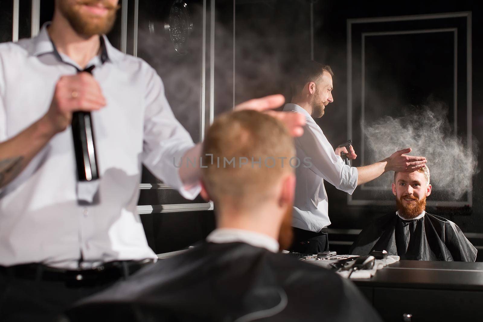 Spraying hair. Portrait of a barber spraying water on the hair of the client. by StudioPeace