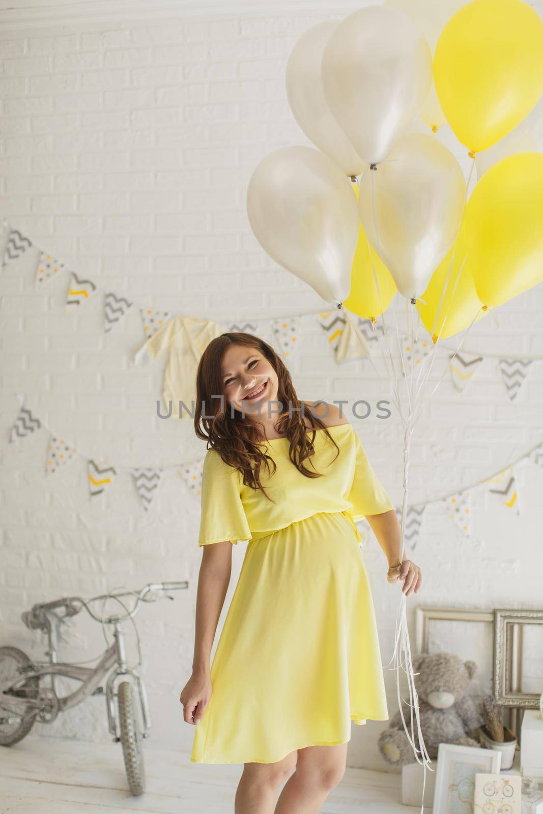 Beautiful pregnant woman in a yellow dress in the Studio.